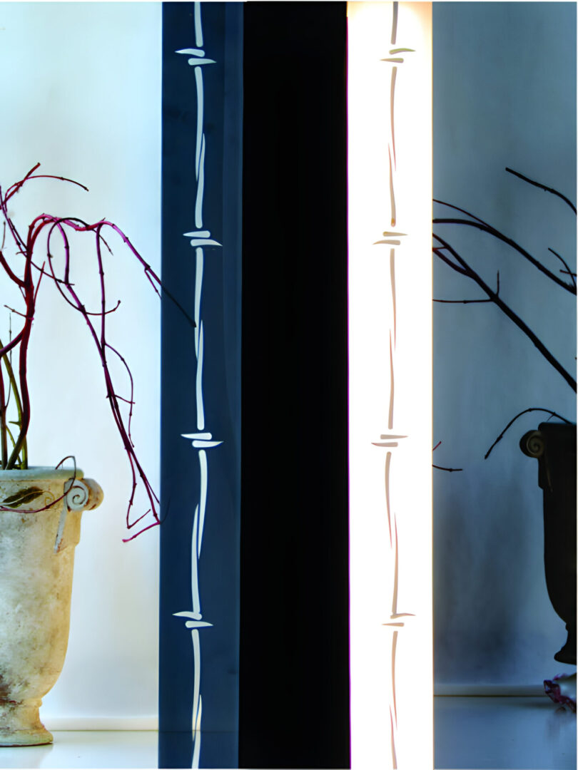 A photograph featuring a vase with twigs next to a vertical neon light installation.
