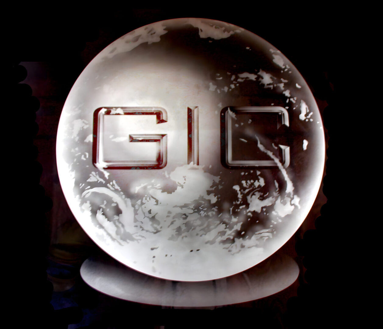 A metallic circular object with the letters "gic" embossed in the center, highlighted against a dark background.