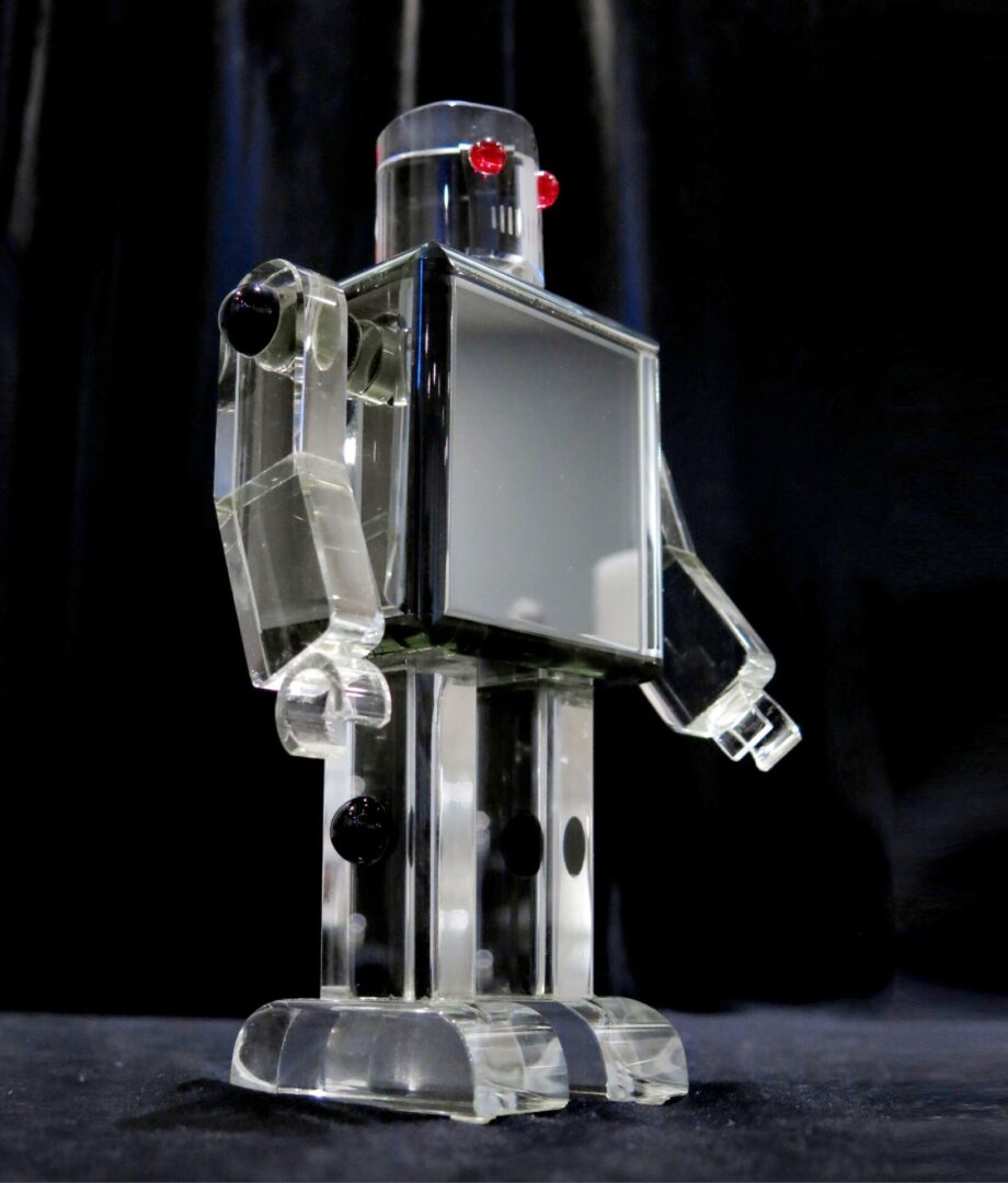 Transparent plastic robot model against a black background.