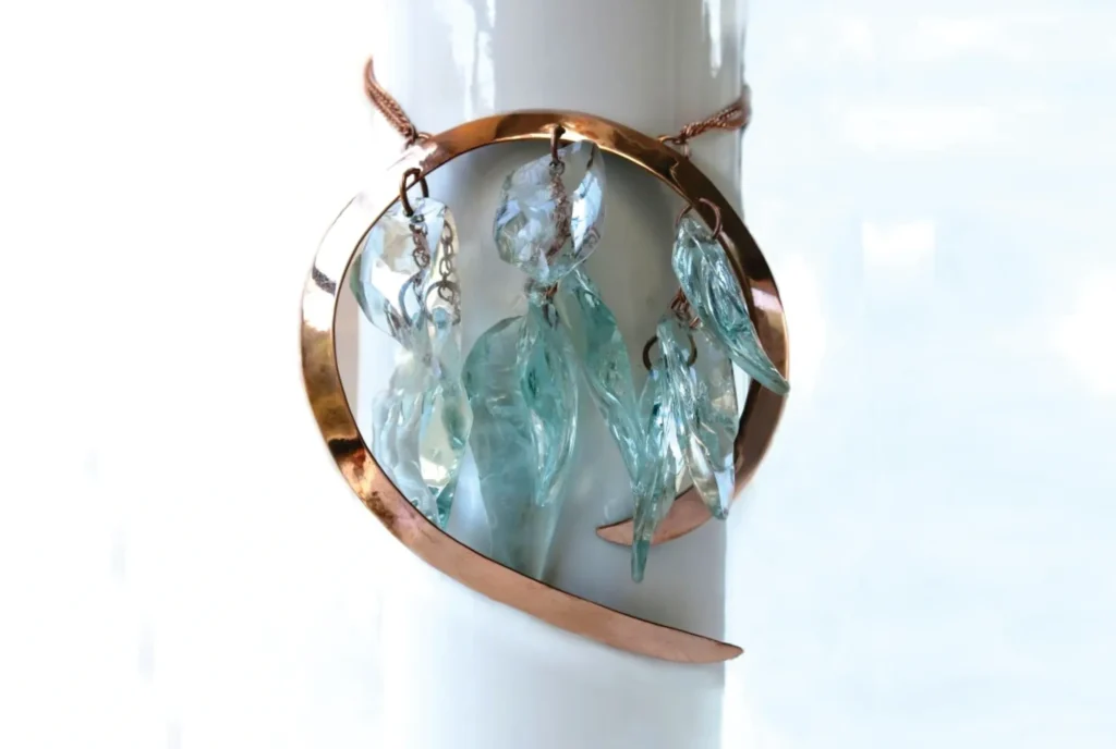 A copper wire art piece with blue glass accents displayed against a white background.