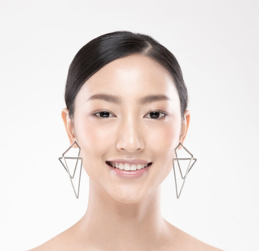 Portrait of a smiling woman with geometric earrings.