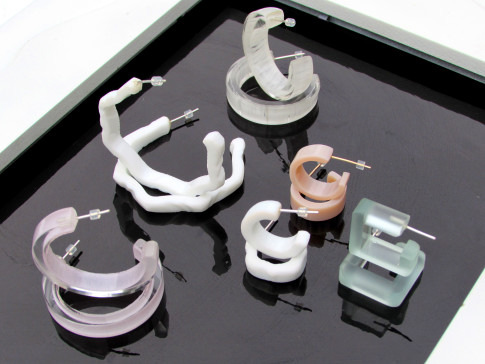 An assortment of modern, uniquely shaped bracelets displayed on a reflective surface.