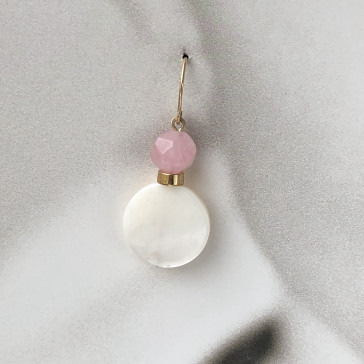 A single hoop earring with a pink and white pendant on a gray fabric background.