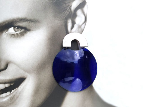 Black and white photo of a smiling woman with a large, blue-colored earring superimposed.
