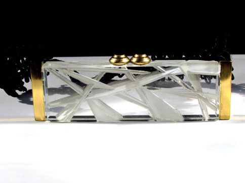 Crystal clutch bag with golden clasp on a reflective surface.