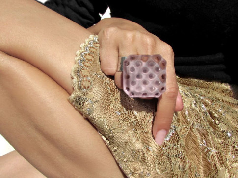 A person holding a bitten piece of chocolate while wearing a sequined garment.