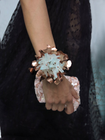 A person wearing a large, intricate bracelet with a prominent gemstone centerpiece on their wrist.