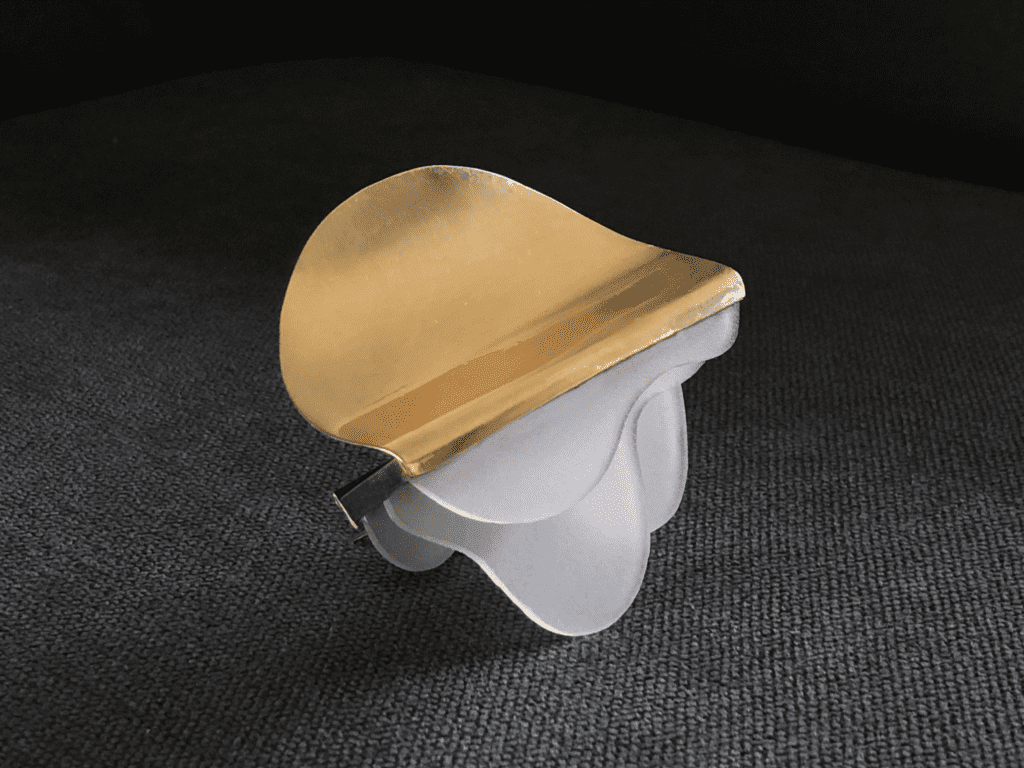 A frosted glass lampshade with a gold-colored metal clip on a dark surface.