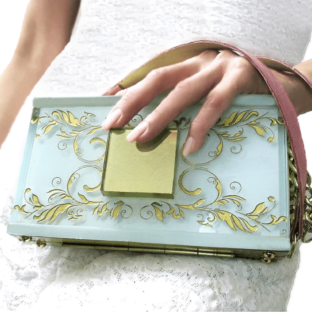 A woman holding onto a blue purse with gold designs.