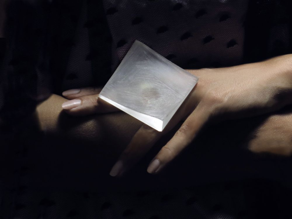 A person's hands cradling a translucent cube that catches the light.
