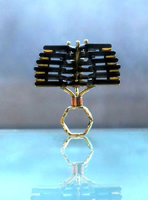 A gold ring with black sticks on top of it.