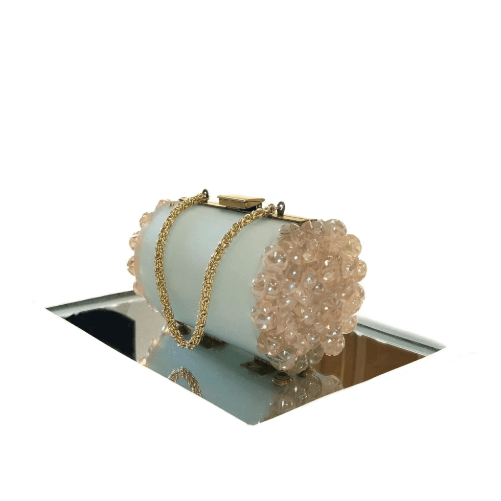 A white and pink purse sitting on top of a mirror.
