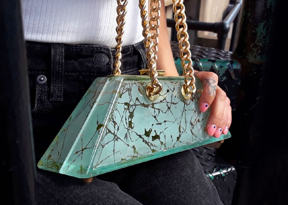 A woman holding a purse with gold chain handles.