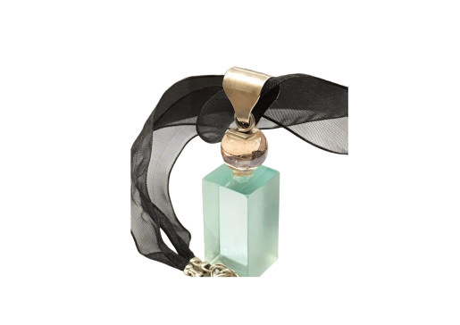 Transparent perfume bottle with a black ribbon and golden accents on a white background.