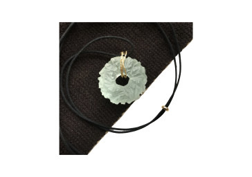 Silver ruffled circular pendant on a black cord necklace against a dark background.