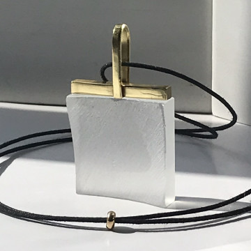A square marble pendant with a gold bail on a black cord necklace.